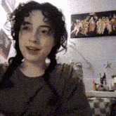 a girl with pigtails is smiling in front of a wall with a painting of angels on it