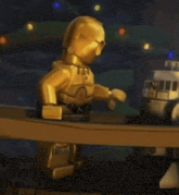 a golden lego figure is standing on a wooden deck .