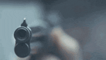 a person is pointing a gun at the camera in a blurry photo .