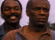 a couple of men are standing next to each other and smiling .