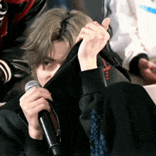 a person holding a microphone and covering their face