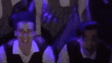 a group of people are sitting in a dark room with purple lights on .