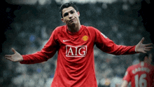 a soccer player wearing a red aig jersey holds his arms out