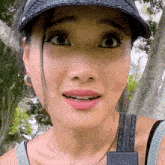 a woman wearing a hat and earrings is looking at the camera .