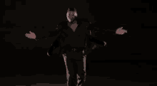a man in a suit is dancing in the dark with his arms outstretched .