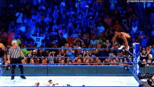 a wrestler is jumping over a referee in a wrestling ring with the next big thing written on the bottom right