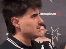 a man is talking into a microphone while standing in front of a wall .