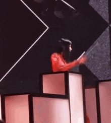 a man in a red shirt is holding a drum stick in his hand on a stage .