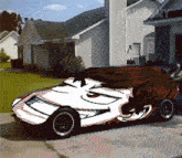 a car with a face painted on it is parked in front of a house with failarmy written on it