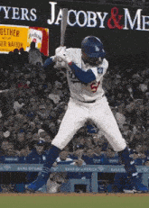 a baseball player getting ready to swing at a ball in front of a sign that says jacoby & me