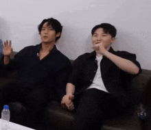 two men are sitting next to each other on a couch .