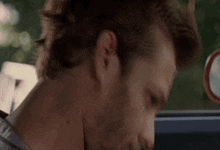 a man with a beard is sitting in a car and looking down at something .