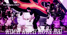 a group of people are dancing on a stage with the words kuch kuch hota hai written on the bottom .