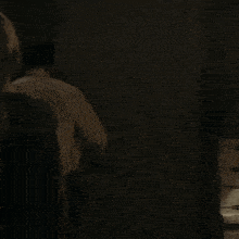 a man in a white shirt stands in a dark room and says " hey guys "