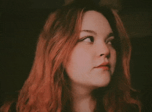 a woman with red hair looks at the camera