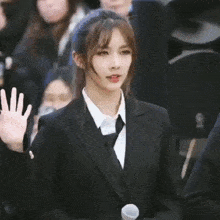 a woman in a suit and tie is standing in front of a crowd .