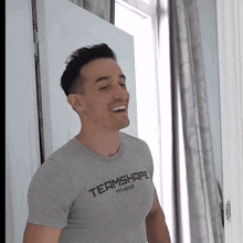 a man wearing a gray teamshape fitness shirt smiles