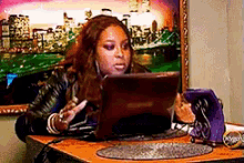 a woman is sitting at a desk looking at a laptop computer