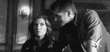 a black and white photo of a man and a woman standing next to each other .