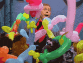 a man is surrounded by colorful balloons including a monkey
