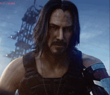 a man with long hair and a beard stands in front of a screen that says r 21 22:03