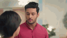 a man in a red shirt is standing next to a woman in a room .