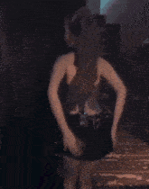 a woman in a silver top and black shorts is dancing in a dark room