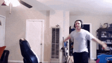 a man wearing headphones and a white shirt is dancing in a living room