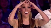 a woman is making a funny face with her hands on her head .