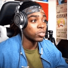 a man wearing headphones is sitting in front of a wall with wanted posters on it