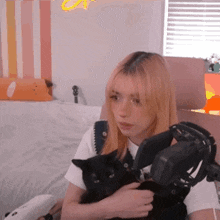 a woman is holding a black cat in her arms while wearing headphones and a microphone .