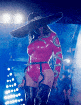 a woman wearing a cowboy hat and a pink bodysuit holds a microphone