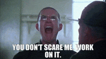 a man with glasses is screaming at another man with the words `` you don 't scare me , work on it '' .