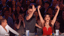 a woman in a red dress is sitting in front of a crowd with her arms in the air and a cup that says lavazza