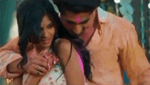 a man and a woman are hugging each other and the woman is holding the man 's chest .