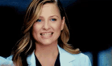 a close up of a woman wearing a white lab coat and smiling .