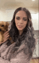 a woman in a pink sweater is petting a small dog