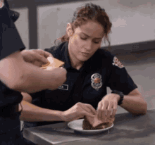 a woman in a police uniform is sitting at a table with a plate of food
