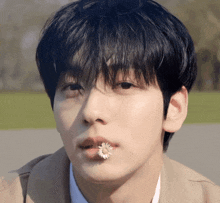 a man with a flower in his mouth looks at the camera
