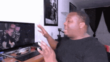 a man is sitting at a desk in front of a computer and a television .