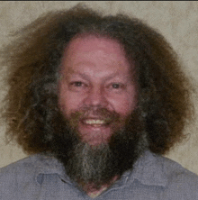 a man with long hair and a beard is smiling .