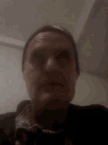 a man wearing a beanie and a jacket is taking a selfie in a dark room .