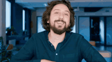 a man with a beard wearing a blue shirt smiles