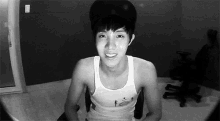 a black and white photo of a young man in a tank top and hat .