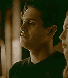 a man and a woman are standing next to each other and the man is looking at the woman .
