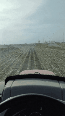 a tractor is driving down a dirt road with a sign in the background that says ' x '