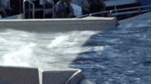 a dolphin is swimming in a pool with people sitting in the background .