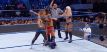 a group of wrestlers are fighting in a wrestling ring with a referee in the background .