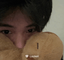 a close up of a person covering their face with a teddy bear with the word locket on the bottom