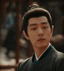 a man with a bun on his head is wearing a black jacket